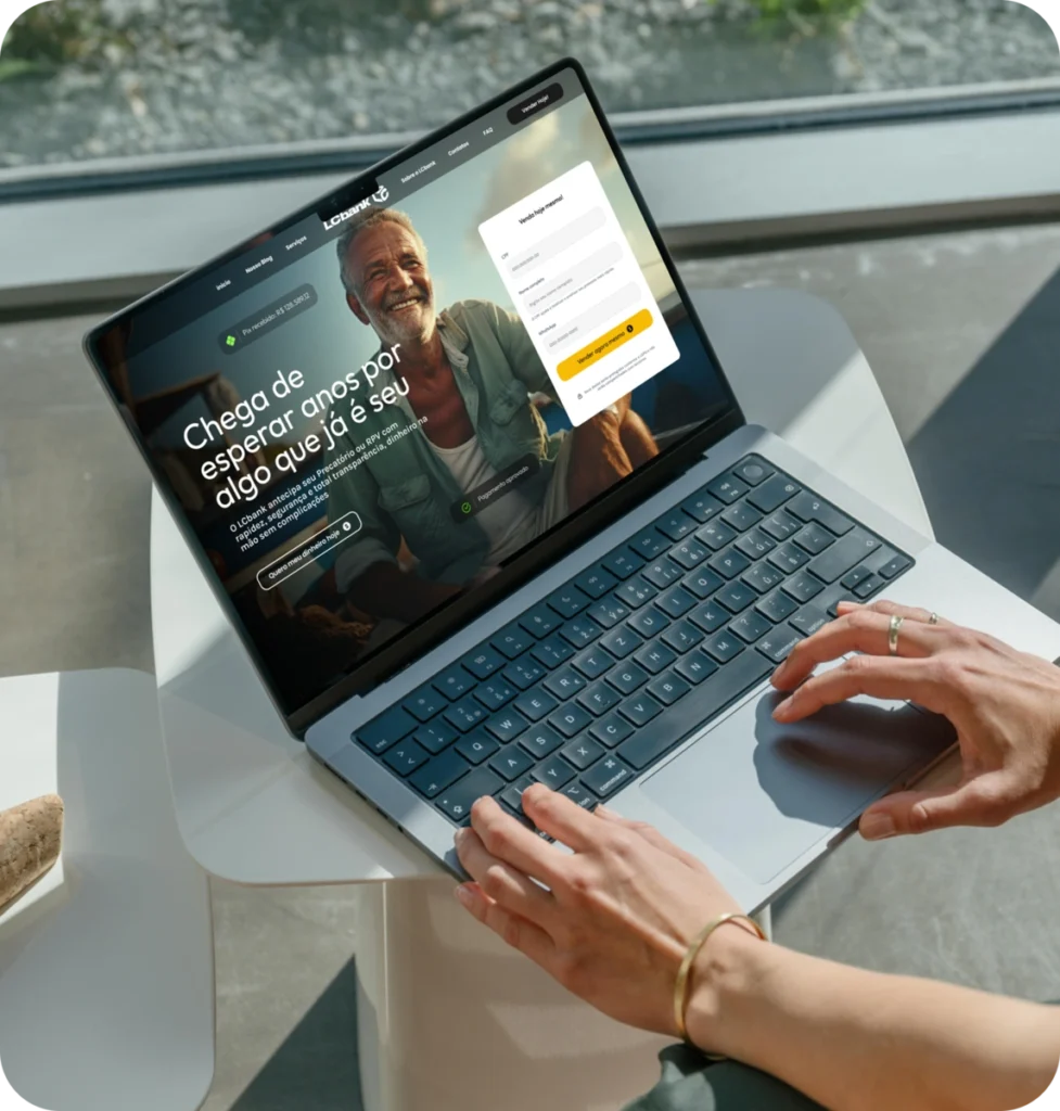 Mãos de uma pessoa digitando em um laptop mostrando um site de banco